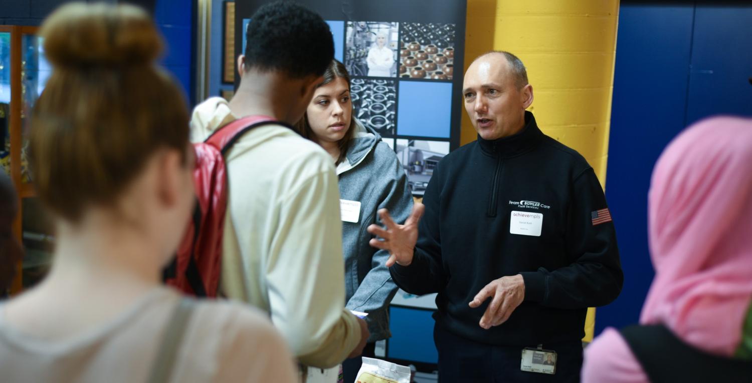 A man at a school career fair talks with students 