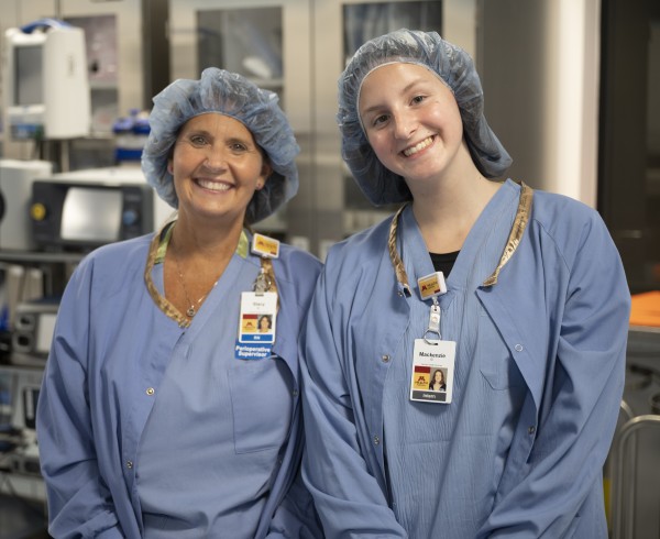 Supervisor and intern standing side by side in scrubs, smiling at camera